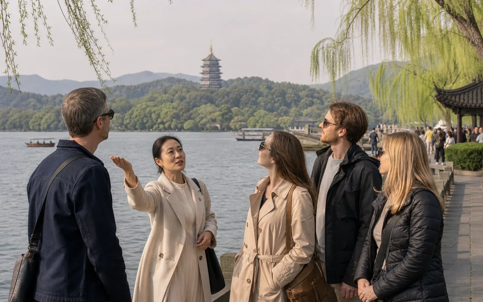 Travelers with a Hangzhou guide beside West Lake with Leifeng Pagoda and willow trees