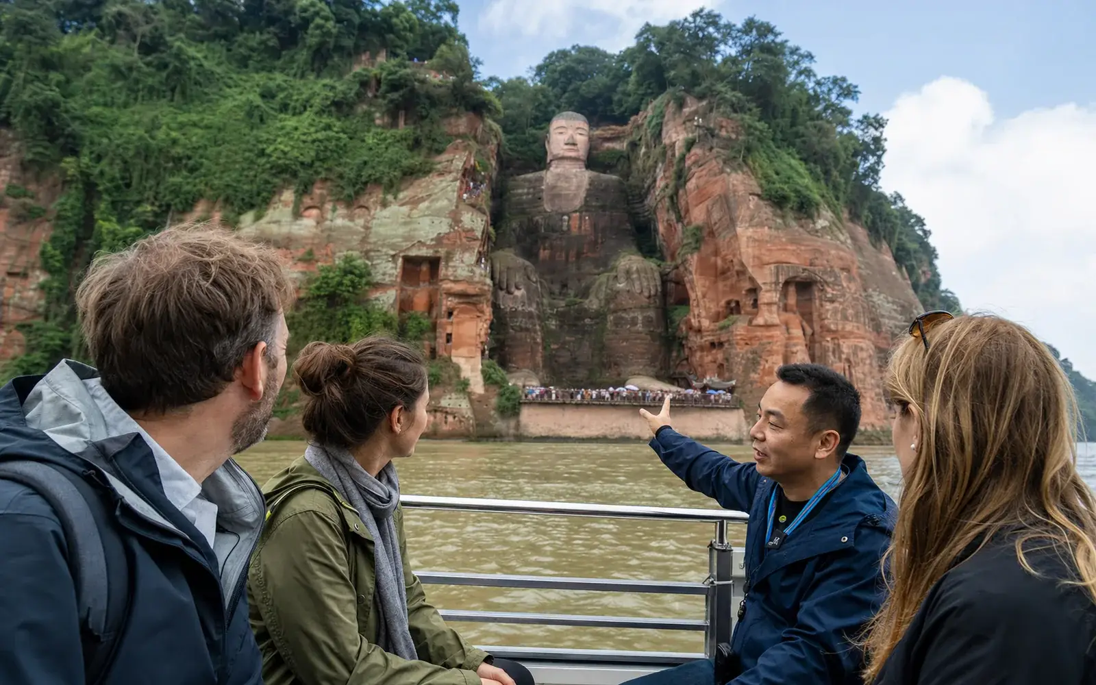 Travelers with a Sichuan guide viewing the Leshan Giant Buddha from the river