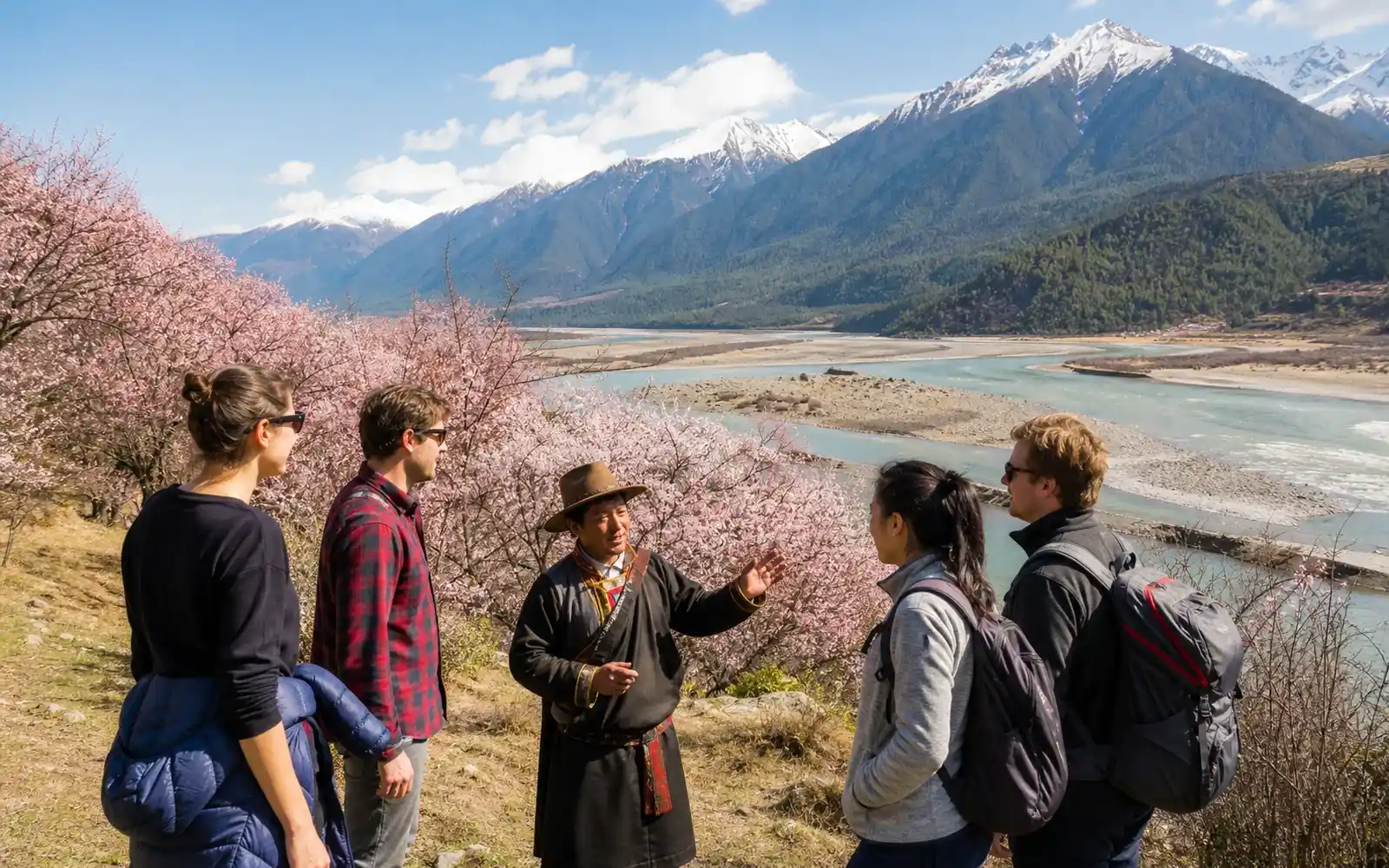 Travelers among Nyingchi peach blossoms with Himalayan foothills behind