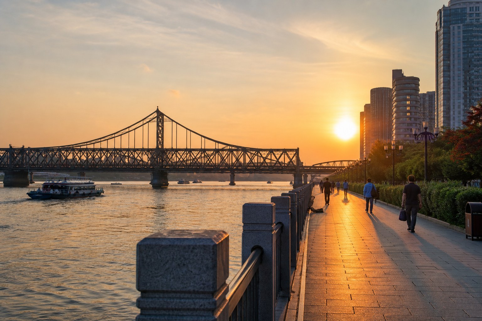 Dandong promenade, historic steel bridge and Yalu River in golden-hour light