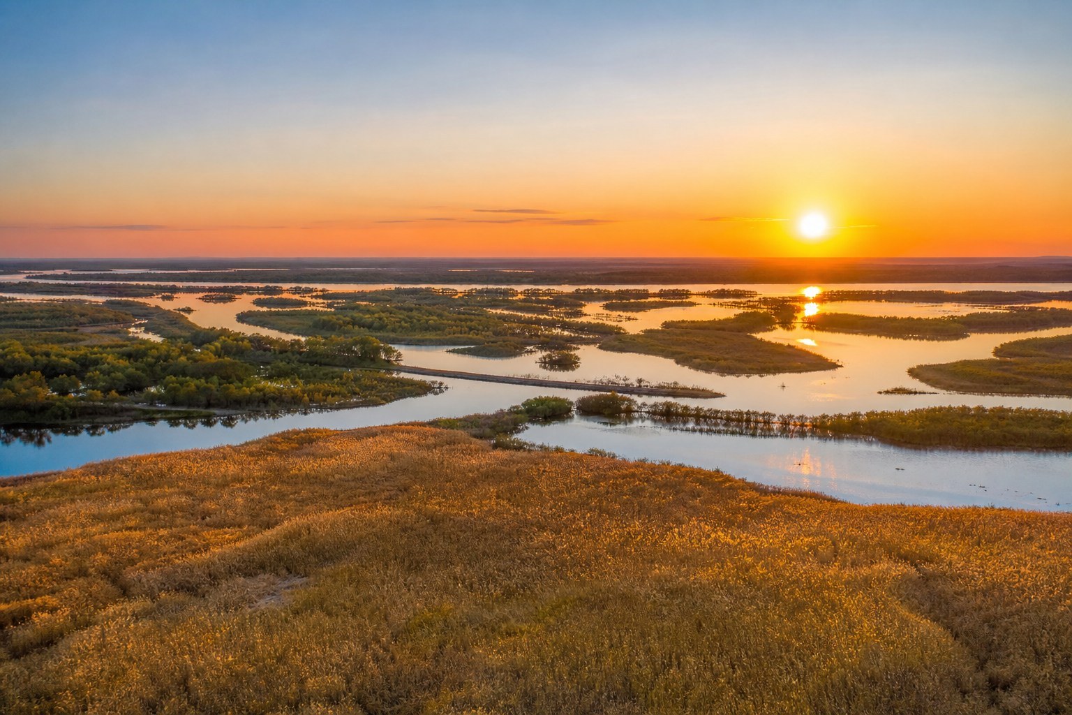 Sunrise over the immense river confluence and golden wetlands near Fuyuan