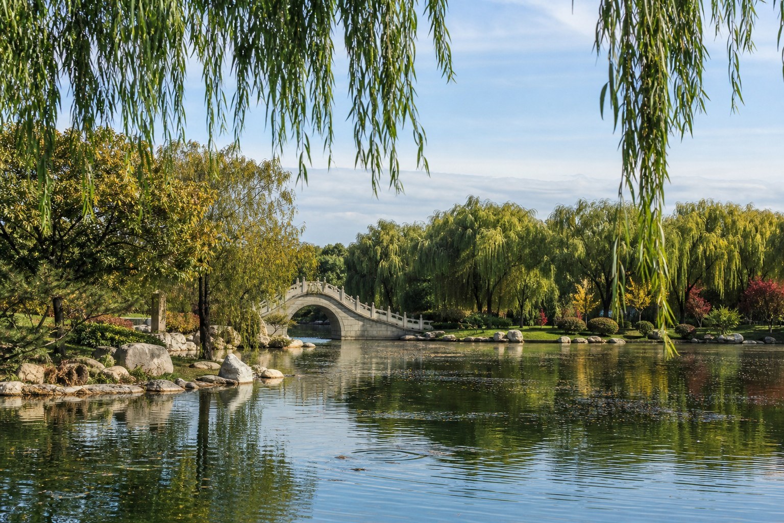 Willow-lined lake, stone bridge and tranquil landscaped gardens in Beiling Park