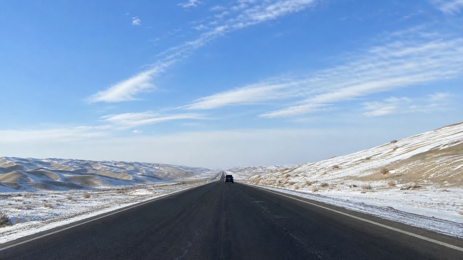 S21 Desert Highway crossing snow-dusted dunes in Xinjiang