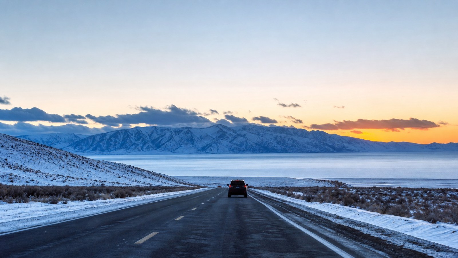 Winter road from Urumqi approaching frozen Sayram Lake at sunset