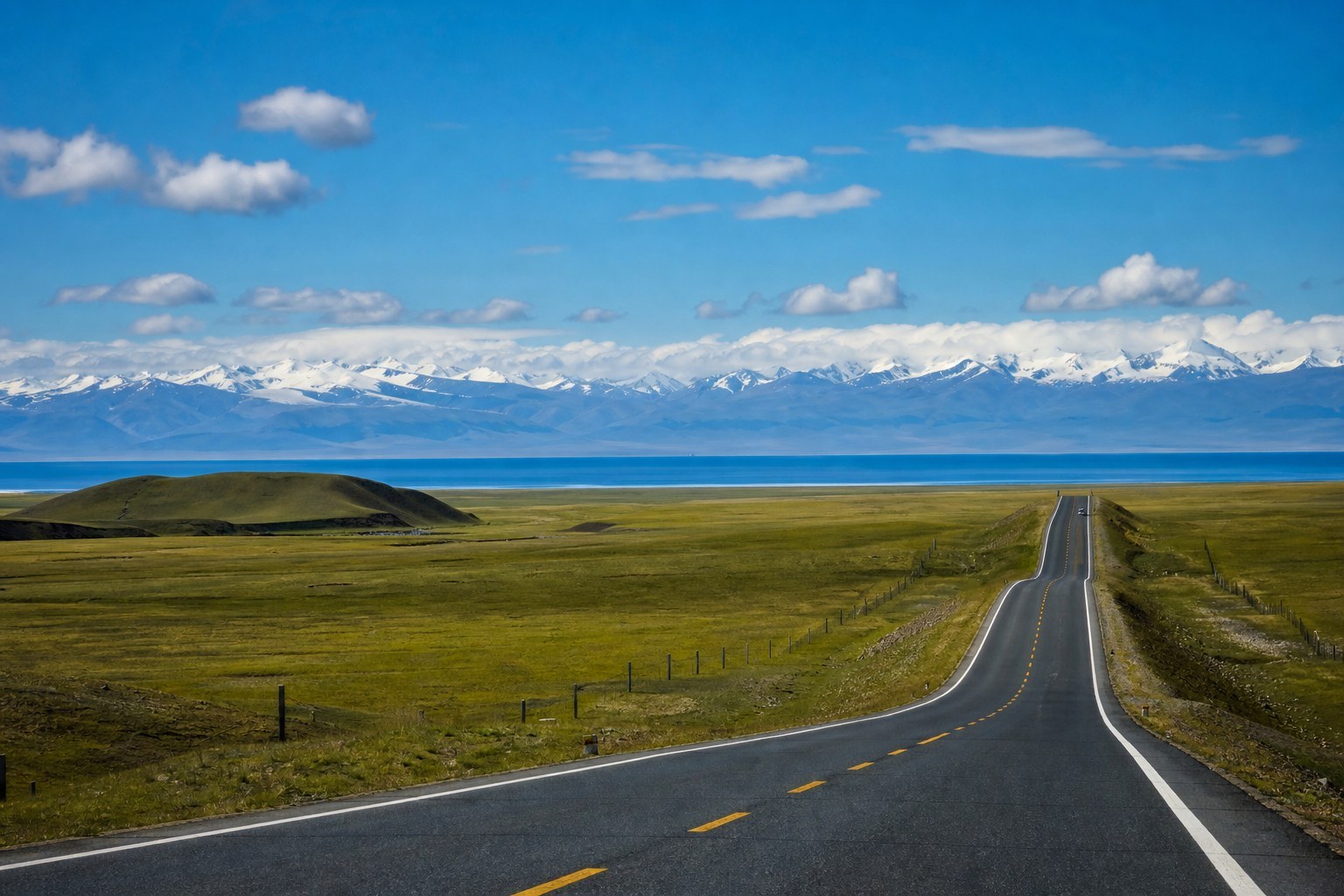 Scenic plateau road with the first view of Qinghai Lake and distant snow mountains