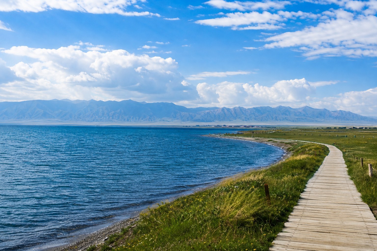 Deep blue Qinghai Lake and a wooden lakeside path beneath distant mountains