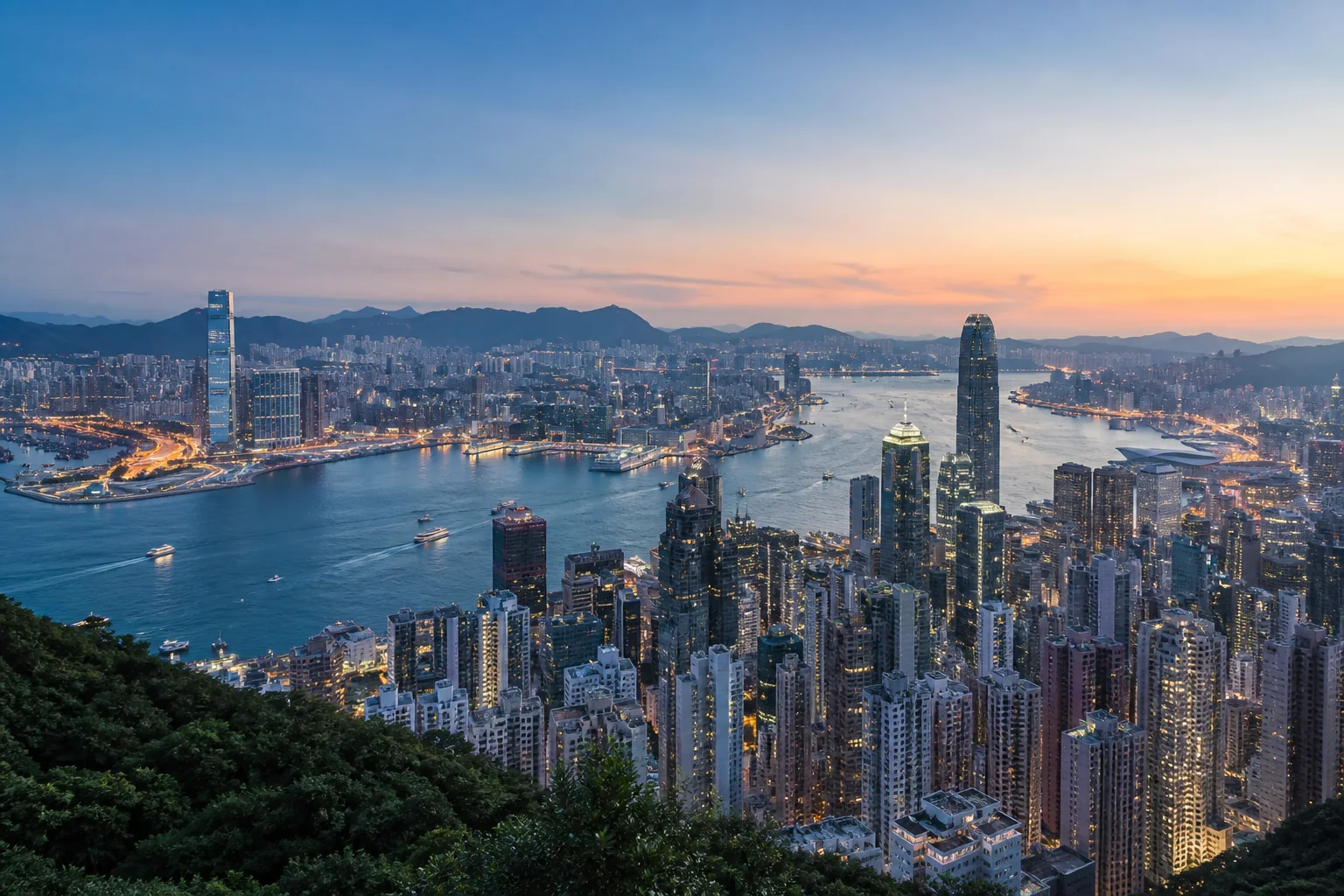 Victoria Harbour and the Hong Kong skyline viewed from an elevated hillside at blue hour