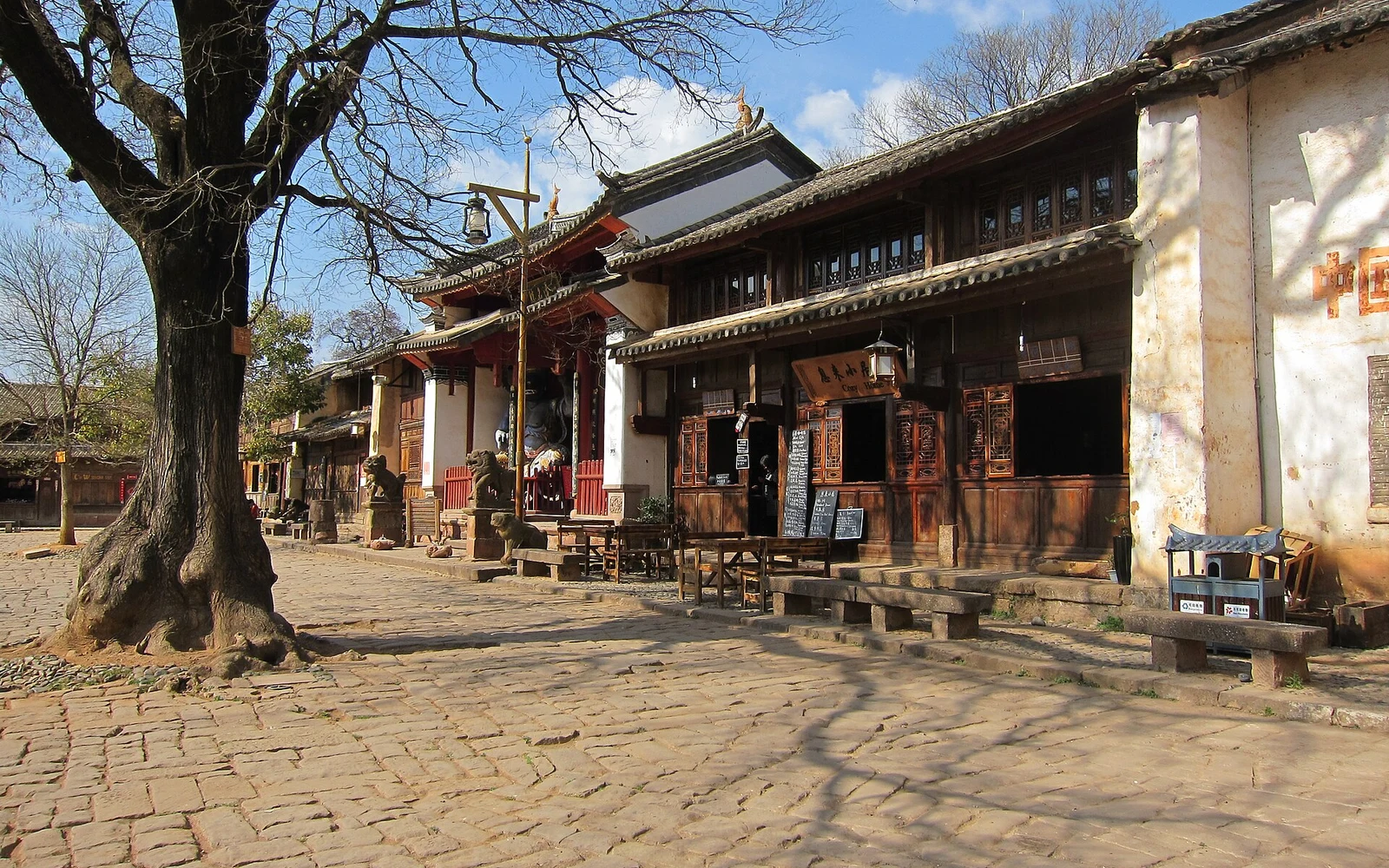 Tree-lined square and traditional buildings in Shaxi