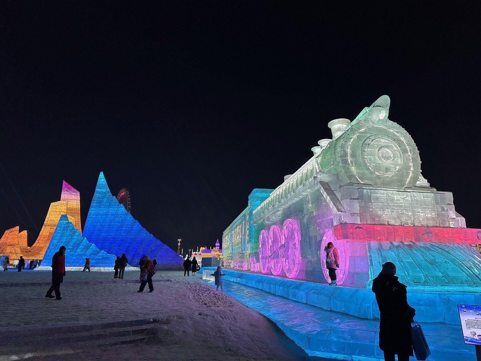 Illuminated ice train and colourful ice buildings at Harbin Ice and Snow World