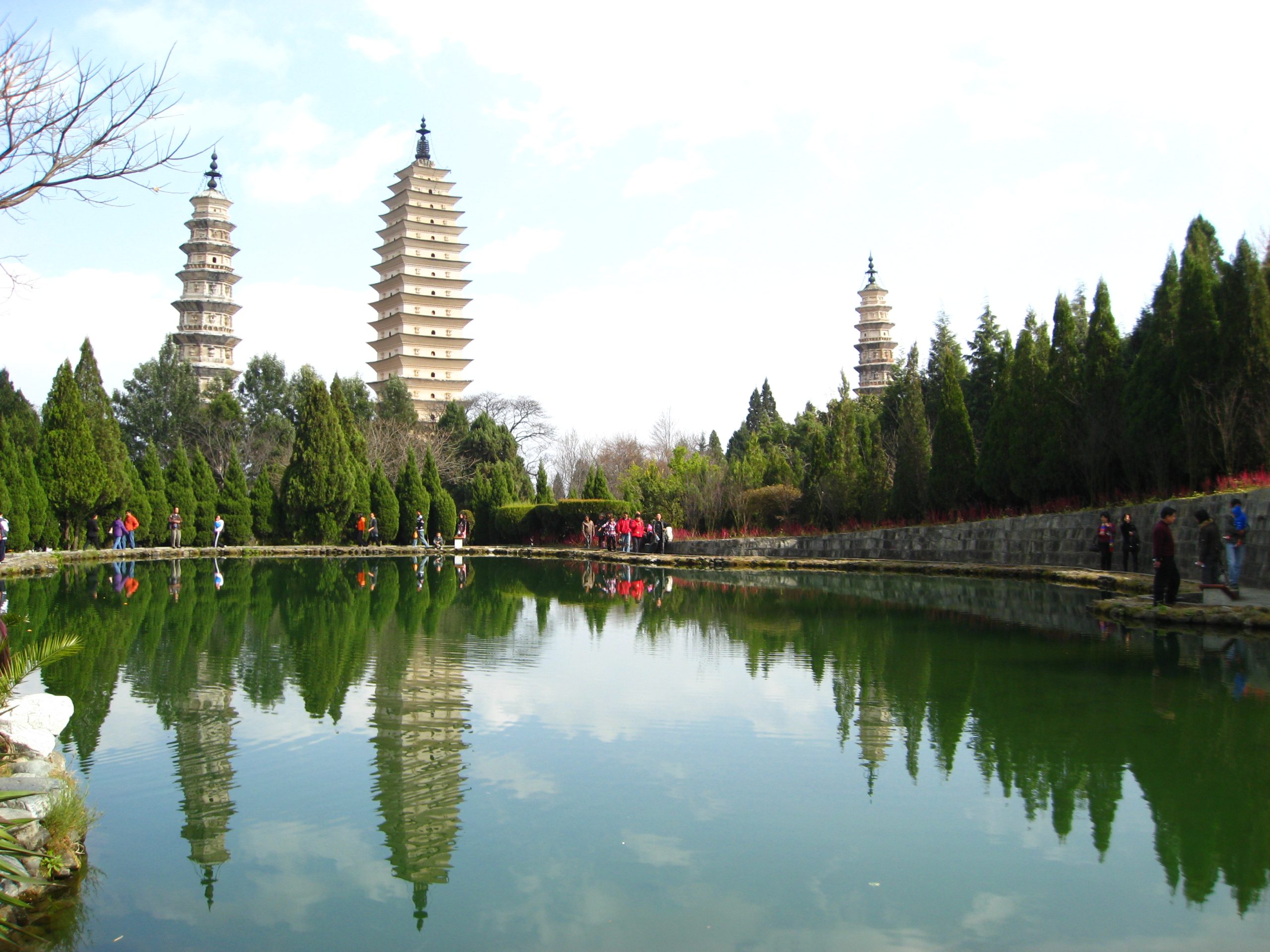 The Three Pagodas in Dali reflected in a pond beside trees
