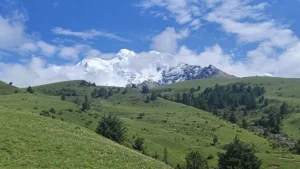 Open pastures beneath the Genyen mountain skyline