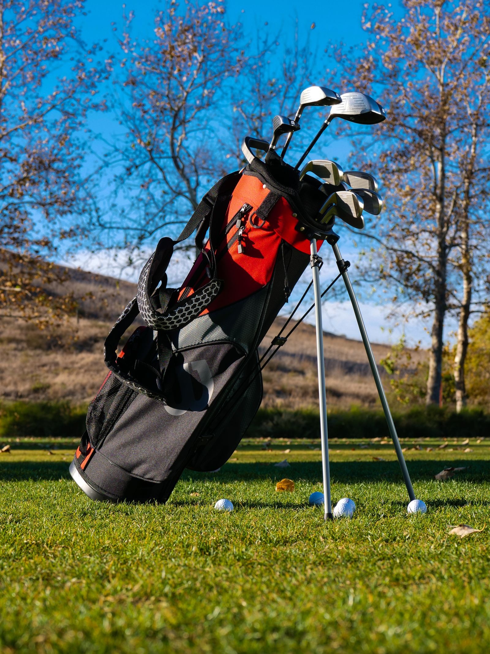 Golf clubs in a red and black bag standing on grass