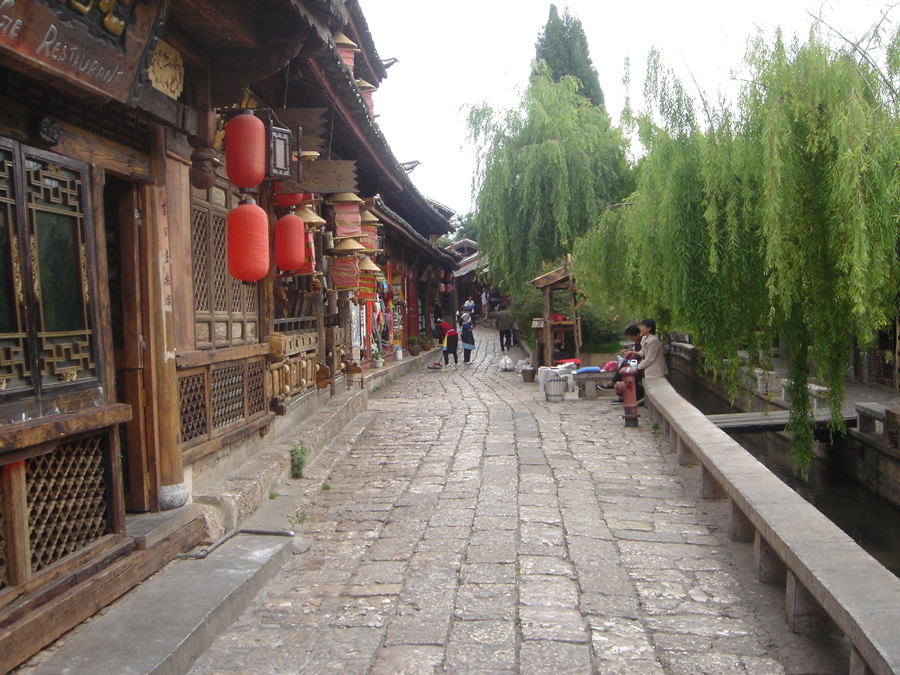 A stone-paved lane beside a canal and wooden buildings in Lijiang Old Town