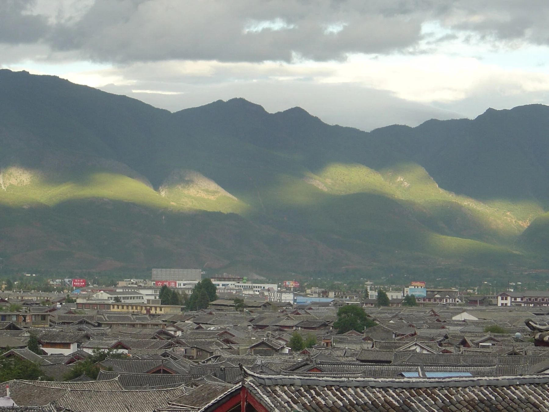 Traditional tiled roofs of Lijiang Old Town with mountains behind