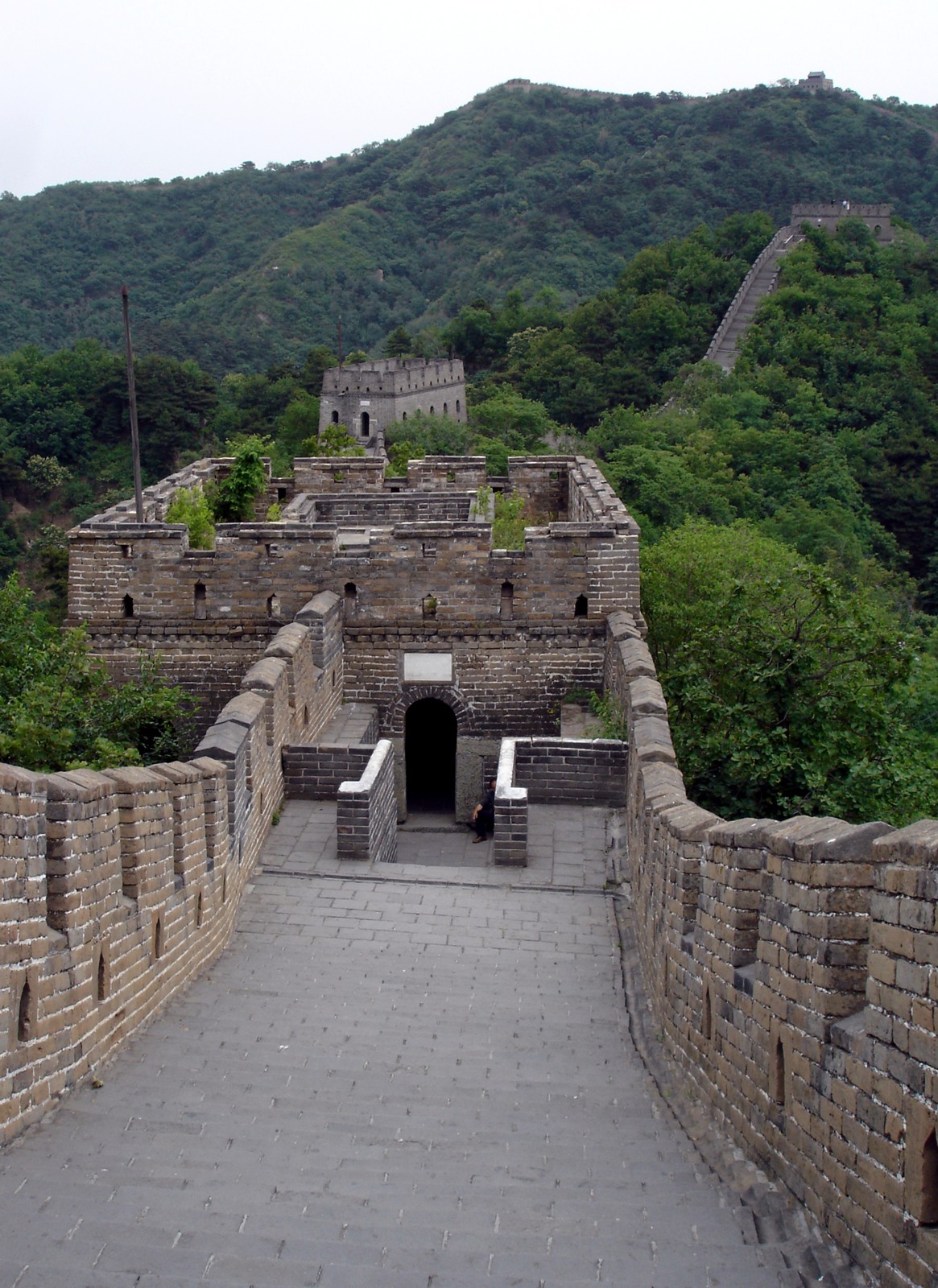 Stone steps descend towards a watchtower and climb the hillside at Mutianyu