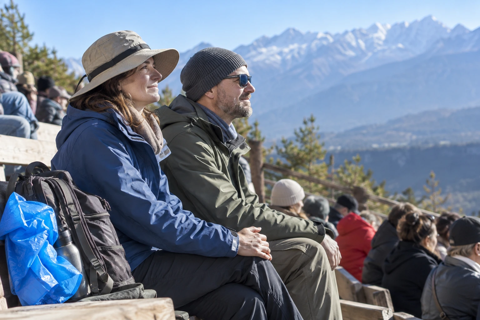 Two travelers in jackets and hats sitting outdoors beside a daypack