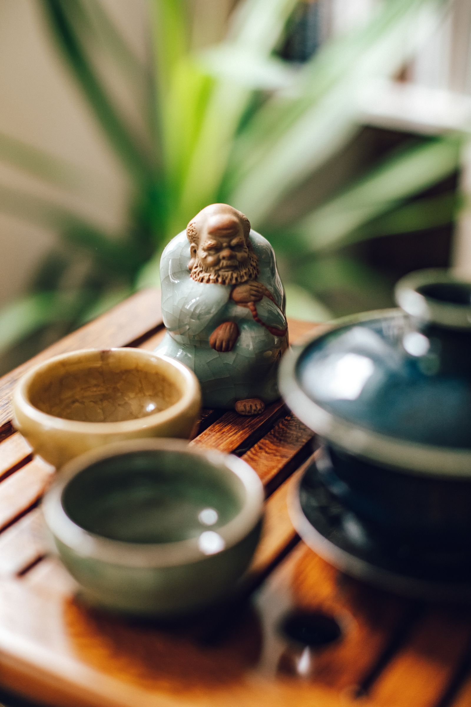 Ceramic cups, a lidded tea bowl and a small figurine on a wooden tea tray