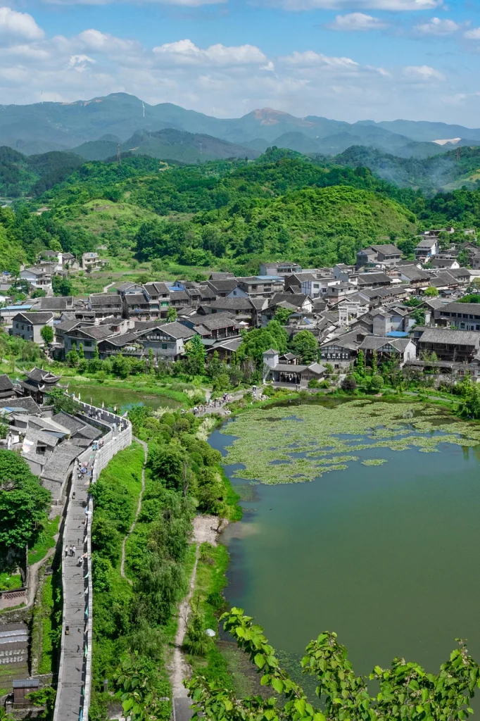 Qingyan stone walls, tiled roofs and a pond below green hills